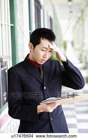Picture - Close-up of a businessman reading mails and looking upset. Fotosearch