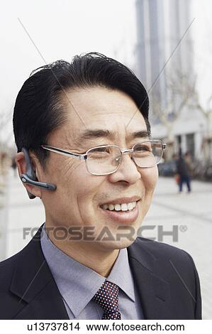 Close-up of a businessman wearing a hands free device smiling View Large Photo Image Picture - Close-up of a businessman wearing a hands free device smiling. Fotosearch