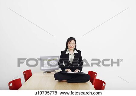 Portrait of a businessman sitting cross-legged on a table with a keyboard and smiling View Large Photo Image Stock Photo - Portrait of a businessman sitting cross-legged on a table with a keyboard and smiling. Fotosearch
