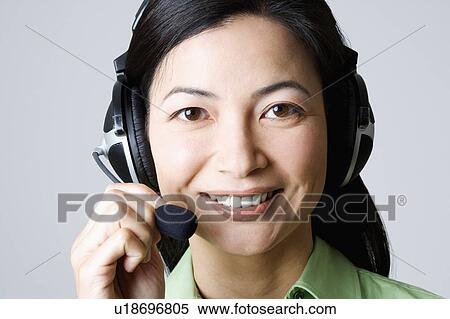 Stock Photography - Portrait of a businesswoman using a headset and smiling. Fotosearch