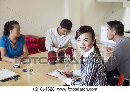 Portrait of a businesswoman with three business executives seated at a conference table View Large Photo Image Stock Photo - Portrait of a businesswoman with three business executives seated at a conference table. Fotosearch