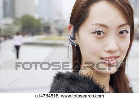 Stock Photo - Portrait of a young woman wearing a hands free device. Fotosearch