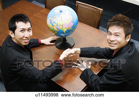Stock Photo - Portrait of two businessmen shaking hands. Fotosearch