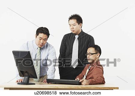 Three businessmen looking at a computer monitor View Large Photo Image Stock Photo - Three businessmen looking at a computer monitor. Fotosearch