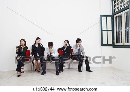Picture - Two businessmen and three businesswomen sitting with mobile phones. Fotosearch