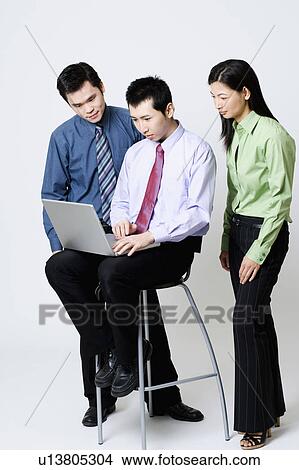 Two businessmen with a businesswoman using a laptop View Large Photo Image Picture - Two businessmen with a businesswoman using a laptop. Fotosearch