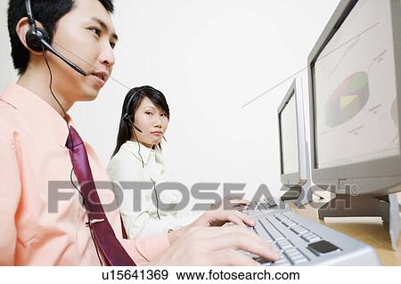 Two customer service representatives working on a computer View Large Photo Image Stock Photo - Two customer service representatives working on a computer. Fotosearch