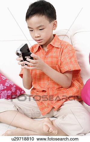 Close-up of a boy holding a digital camera View Large Photo Image Stock Image - Close-up of a boy holding a digital camera. Fotosearch