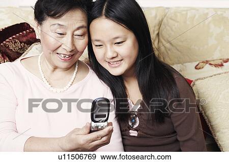 Stock Photo - Close-up of a girl and her grandmother looking at a mobile phone. Fotosearch