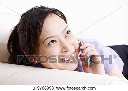 Close-up of a young woman talking on a mobile phone View Large Photo Image Stock Image - Close-up of a young woman talking on a mobile phone. Fotosearch