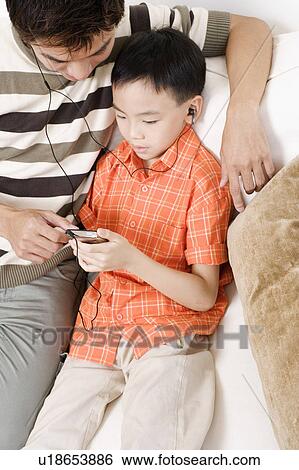High angle view of a mid adult man and his son listening to an MP3 player View Large Photo Image Stock Photograph - High angle view of a mid adult man and his son listening to an MP3 player. Fotosearch