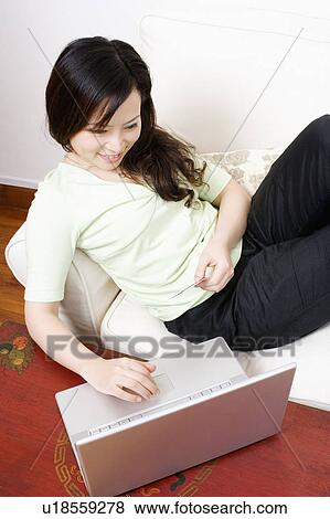 High angle view of a young woman shopping online and holding a credit card View Large Photo Image Stock Photo - High angle view of a young woman shopping online and holding a credit card. Fotosearch