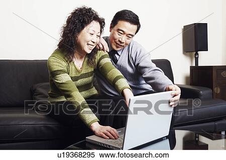 Stock Photography - Mature couple sitting on a couch using a laptop. Fotosearch
