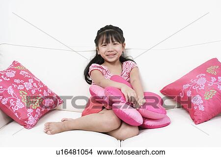 Portrait of a girl sitting on a couch View Large Photo Image Picture - Portrait of a girl sitting on a couch. Fotosearch