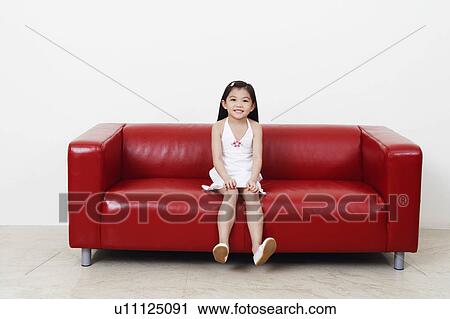 Stock Image - Portrait of a girl sitting on a couch. Fotosearch