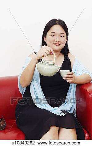 Portrait of a mid adult woman pouring tea from a kettle into the tea cup View Large Photo Image Stock Image - Portrait of a mid adult woman pouring tea from a kettle into the tea cup. Fotosearch