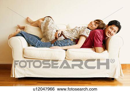 Portrait of a young couple lying back to back on a couch View Large Photo Image Stock Photograph - Portrait of a young couple lying back to back on a couch. Fotosearch