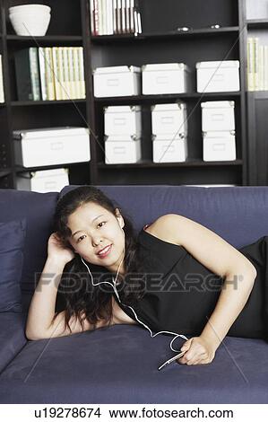 Portrait of a young woman listening to music on headphones View Large Photo Image Picture - Portrait of a young woman listening to music on headphones. Fotosearch
