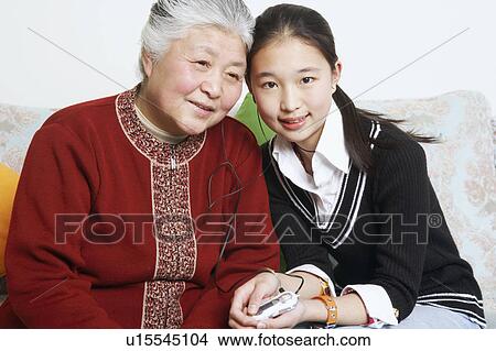Picture - Portrait of a young woman sharing headphones with her grandmother. Fotosearch