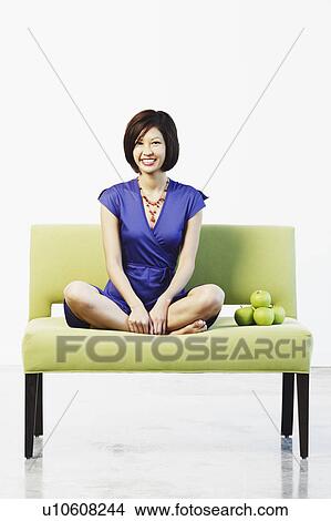 Picture - Portrait of a young woman sitting on a couch. Fotosearch