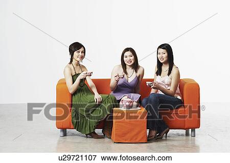 Portrait of three young women sitting on a couch with tea cups View Large Photo Image Stock Photo - Portrait of three young women sitting on a couch with tea cups. Fotosearch