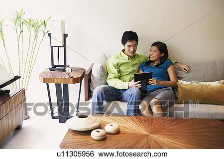 Young couple holding a picture frame and smiling on a couch View Large Photo Image Stock Photograph - Young couple holding a picture frame and smiling on a couch. Fotosearch
