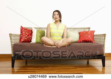 Stock Photo - Young woman sitting on a couch and thinking. Fotosearch