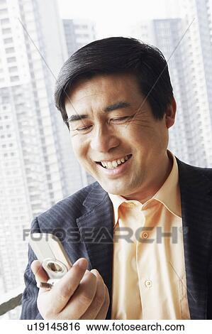 Close-up of a businessman looking at a mobile phone View Large Photo Image Stock Photograph - Close-up of a businessman looking at a mobile phone. Fotosearch