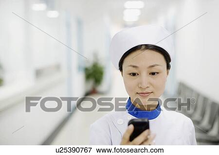 Close-up of a female nurse operating a mobile phone View Large Photo Image Stock Photo - Close-up of a female nurse operating a mobile phone. Fotosearch