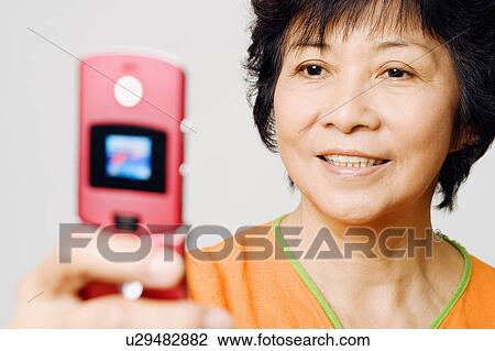 Close-up of a mature woman holding a mobile phone View Large Photo Image Stock Image - Close-up of a mature woman holding a mobile phone. Fotosearch