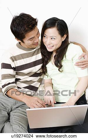 Close-up of a mid adult man embracing a young woman using a laptop View Large Photo Image Picture - Close-up of a mid adult man embracing a young woman using a laptop. Fotosearch
