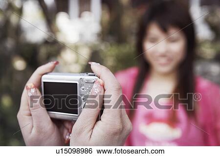 Close-up of a person's hand taking a photograph of a young woman smiling View Large Photo Image Stock Photograph - Close-up of a person's hand taking a photograph of a young woman smiling. Fotosearch