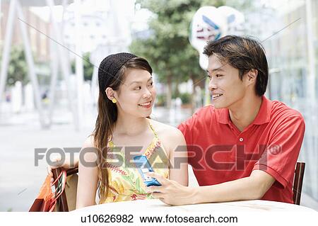 Close-up of a young couple sitting in a cafeteria and smiling View Large Photo Image Stock Image - Close-up of a young couple sitting in a cafeteria and smiling. Fotosearch