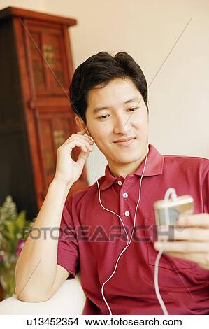Close-up of a young man listening to an MP3 player View Large Photo Image Picture - Close-up of a young man listening to an MP3 player. Fotosearch