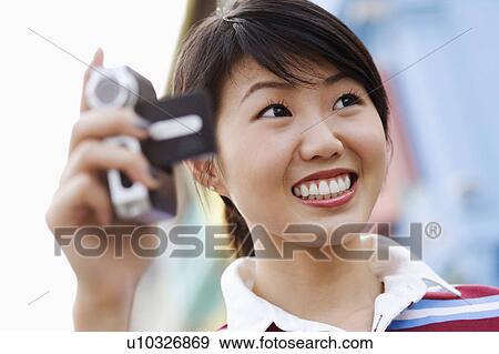 Close-up of a young woman holding a digital camera View Large Photo Image Stock Photo - Close-up of a young woman holding a digital camera. Fotosearch