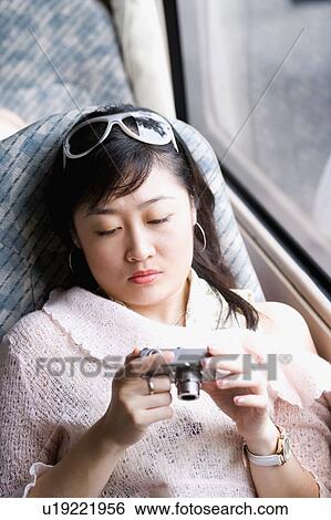 Stock Photograph - Close-up of a young woman holding a digital camera in a car. Fotosearch