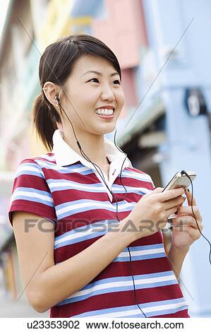 Close-up of a young woman listening to an MP3 player View Large Photo Image Stock Image - Close-up of a young woman listening to an MP3 player. Fotosearch