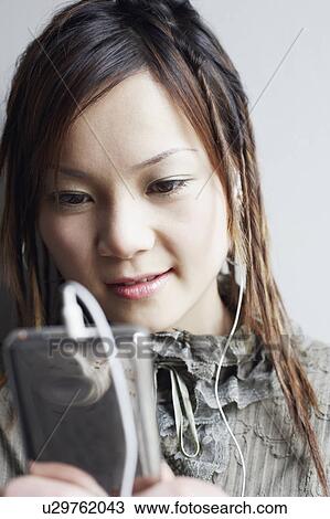 Close-up of a young woman listening to an MP3 player View Large Photo Image Stock Image - Close-up of a young woman listening to an MP3 player. Fotosearch