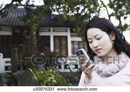 Close-up of a young woman looking at a mobile phone View Large Photo Image Stock Image - Close-up of a young woman looking at a mobile phone. Fotosearch