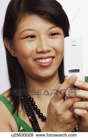 Close-up of a young woman operating a mobile phone View Large Photo Image Stock Photo - Close-up of a young woman operating a mobile phone. Fotosearch