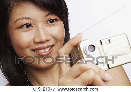Close-up of a young woman smiling and taking a photograph View Large Photo Image Stock Photo - Close-up of a young woman smiling and taking a photograph. Fotosearch