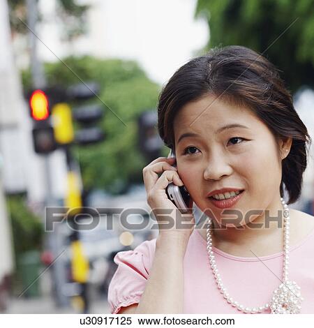 Close-up of a young woman talking on a mobile phone View Large Photo Image Stock Photography - Close-up of a young woman talking on a mobile phone. Fotosearch