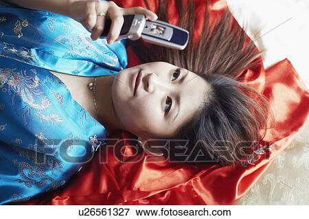 Stock Photo - High angle view of a young woman holding a mobile phone. Fotosearch