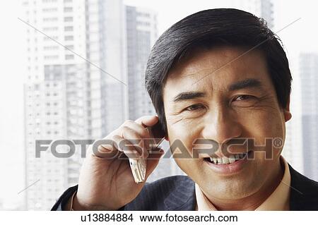Picture - Portrait of a businessman talking on a mobile phone smiling. Fotosearch