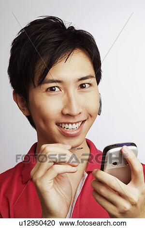 Portrait of a young man smiling and holding a personal data assistant View Large Photo Image Stock Image - Portrait of a young man smiling and holding a personal data assistant. Fotosearch