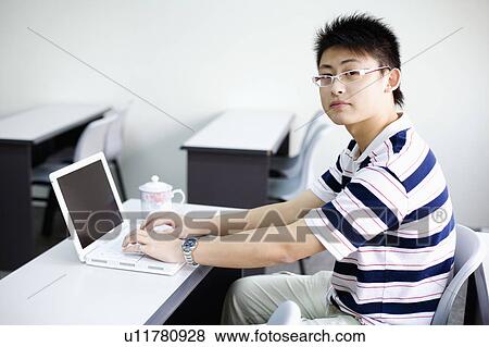 Portrait of a young man using a laptop View Large Photo Image Stock Photo - Portrait of a young man using a laptop. Fotosearch