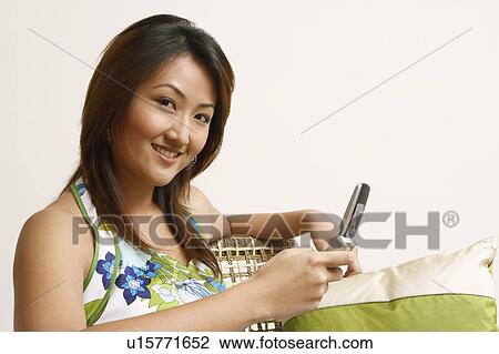 Portrait of a young woman holding a mobile phone View Large Photo Image Stock Image - Portrait of a young woman holding a mobile phone. Fotosearch