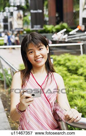 Stock Photo - Portrait of a young woman holding a digital camera and smiling. Fotosearch