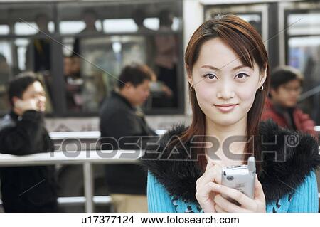 Portrait of a young woman operating a mobile phone with a digitized pen View Large Photo Image Picture - Portrait of a young woman operating a mobile phone with a digitized pen. Fotosearch