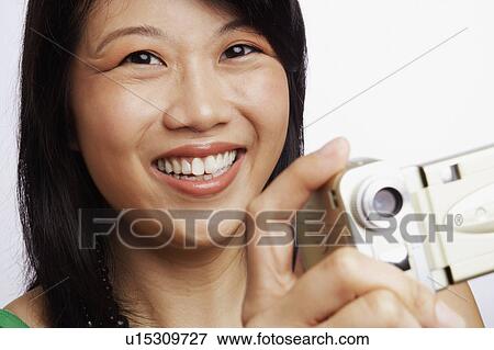 Portrait of a young woman smiling and taking a photograph View Large Photo Image Stock Photo - Portrait of a young woman smiling and taking a photograph. Fotosearch